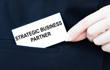 A businessman puts a business card with a STRATEGIC BUSINESS PARTNER in his pocket.