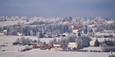 Landscape with snow covered trees around Hoff Medieval Church at Toten, Norway.