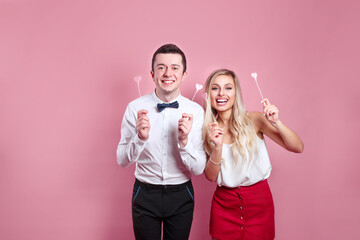 Valentines day. Young happy couple holding pink love hearts over eyes
