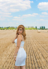 Natural modern plus size woman with full hips, pretty figure in white costume at field. Concept of femininity