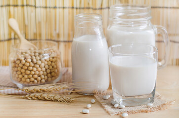 Closed up fresh organic soybean milk in glass bottle with fresh seeds on wooden background in soft...