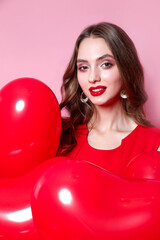 Happy Valentines Day. Beauty girl with red hearts balloons smiling on pink background