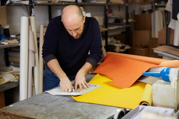 Fototapeta na wymiar craftsman cutting leather with cutter in workshop