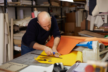 craftsman cutting leather with cutter  in workshop
