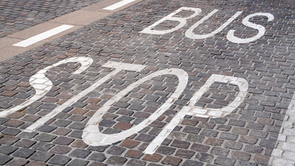 Bus stop sign painted on the tiles on the road.
