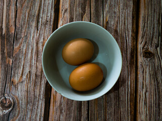 Two eggs in a bowl on a rustic wooden background