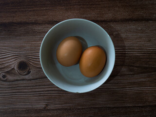 Two eggs in a bowl on a wooden surface