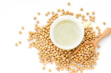 Obraz na płótnie Canvas Top view of fresh delicious homemade soybean milk in soft yellow cup with dry soybean seeds on white background
