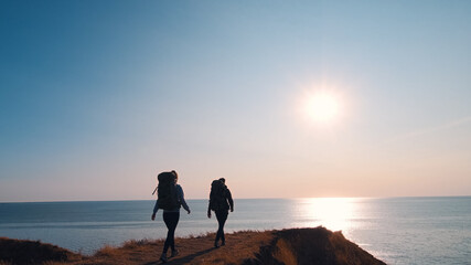 The man and woman walking on the mountain against the sea landscape