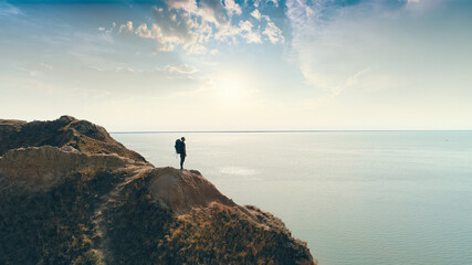 The hiker standing on a mountain on the sea sunshine background
