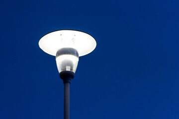 Bright glowing street lamp against the dark blue sky