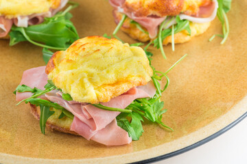 Small rose shaped stuffed omelette, cooked in the microwave oven, with rocket salad, speck - cooked ham (ingredients: eggs, cream, salt, emmental). Italian food