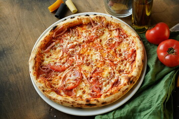Pizza on a dark wooden background with tomatoes