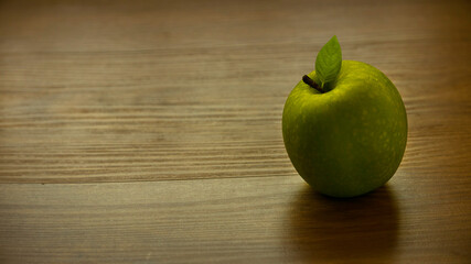 Green, juicy apple on wooden background with copy space.