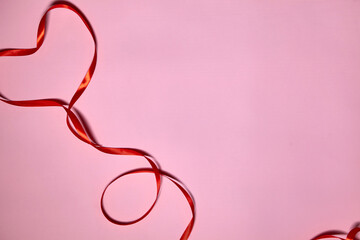 Heart made of red ribbon on pink background, top view. Festive decoration. Heart shaped Ribbon. Valentines day greeting card