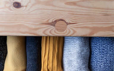 Open wooden dresser drawer with warm knitted woolen clothes. Home vertical storage. Wardrobe...