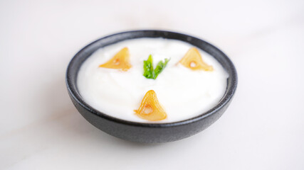 Garlic sauce in a bowl with few pieces of garlic topping.