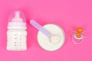 Composition with feeding bottle of baby milk formula on pink background