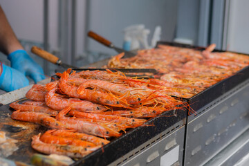 Process of cooking fresh red langoustine shrimps, prawns on grill at summer local food market - close up. Outdoor cooking, barbecue, gastronomy, seafood, cookery, street food concept