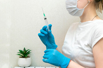 Female doctor in protective blue gloves hold medicine syringe with vaccine on white background. Concept of vaccination and healthcare.