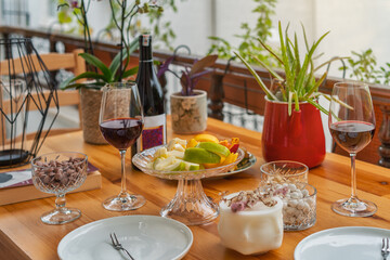 Valentines day table. Wine concept. Serving dinner on the outdoor veranda. Summer mood. Two glasses of red wine and a bottle on the table. Romantic valentines day concept