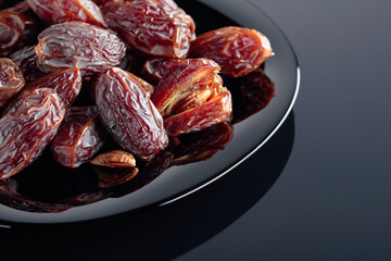 Dried sweet dates on a black plate.