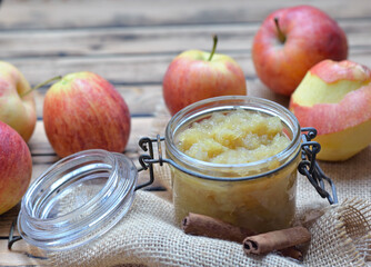  homemade compote in a glass jar with red apples  and cinnamon on a wooden table
