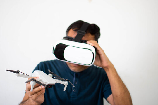 An alone man holds a drone and plays VR to operate the drone. The young man was happy while watching a tutorial on how to flying with VR. Virtual reality wearing a male head. Copy space for design.