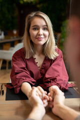 Happy girl in elegant dress looking at her boyfriend while holding his hands