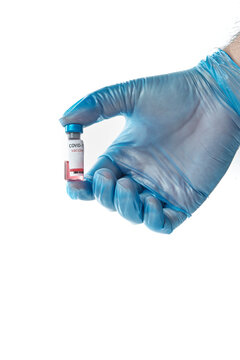 Nurse's hand with blue gloves holding a vial of COVID-19 vaccine.
