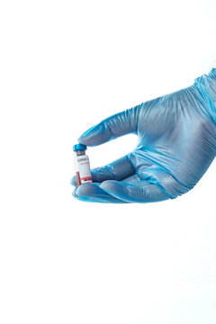 Nurse's hand with blue gloves holding a vial of COVID-19 vaccine.