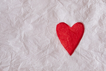 White crumpled paper cut and red heart underneath. White crumpled paper texture background.