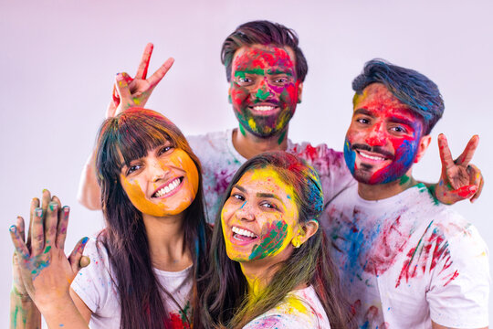 four indian students painted in colors celebrating holi festival in studio white isolate background