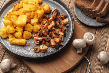 Vegetarian dish fried potatoes with mushrooms served unmixed in a concrete plate