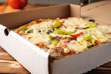 Vegetarian pizza with paprika on wholegrain dough in a cardboard box, close-up