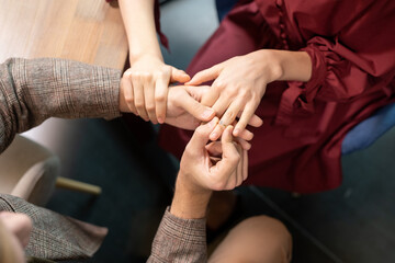 Obraz premium Hands of guy putting engagement ring on finger of his girlfriend during dinner