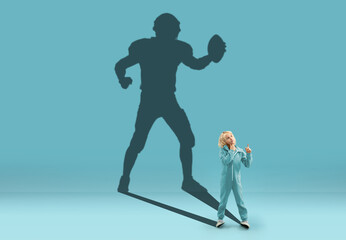 Childhood and dream about big and famous future. Conceptual image with boy and shadow of sportive male american football player on blue background. Childhood, dreams, imagination, education concept.