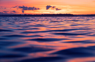 Water surface. View of a Sunset sky background. Dramatic gold sunset sky with evening sky clouds over the sea. View of a Crystal clear sea water texture. Landscape. Small waves. Water reflection