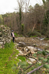 Young sporty female hiking through a valley close to a river. Athletic young woman walking in the countryside during the winter in Spain.