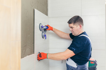 A male construction worker installs a large ceramic tile