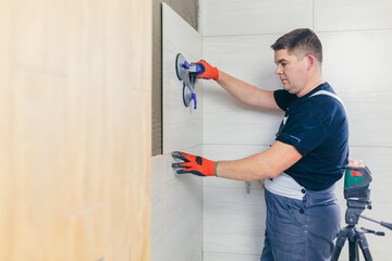 A male construction worker installs a large ceramic tile