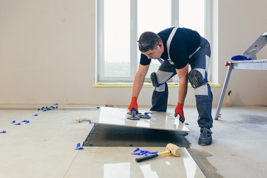 A male construction worker installs a large ceramic tile
