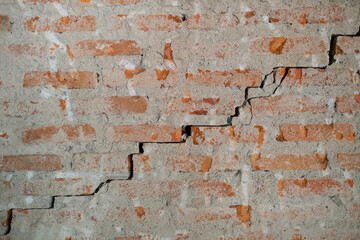 Naklejka premium Brick wall cracks in concrete cement wall in the house where no people to live. White cement construction material texture. Detail of ruin and destruction. Texture of crack in the old wall