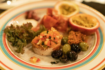 Classic Italian appetizer dish; bruschetta with heirloom tomatoes and olives in warm light romance restaurant dinner.