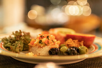 Classic Italian appetizer dish; bruschetta with heirloom tomatoes and olives in warm light romance restaurant dinner.