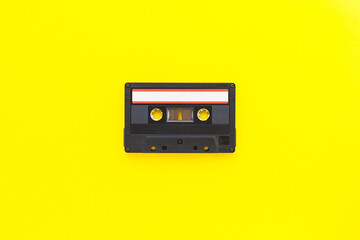 Retro audio tape cassette from 80s and 90s isolated on yellow background. Old technology concept. Flat lay, top view with copy space.