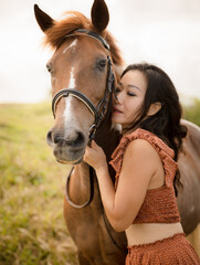 Obraz premium Portrait of Asian woman and brown horse. Woman hugging and kissing horse. Closed eyes. Romantic concept. Love to animals. Nature concept. Bali, Indonesia