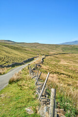 Remote, narrow moorland road in bleak and treeless hilly landscape