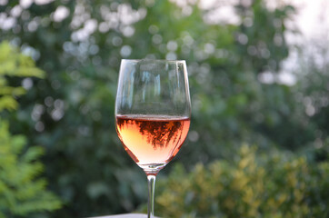 Detailed view of a glass of rosé wine. View of the forest from the chalice.