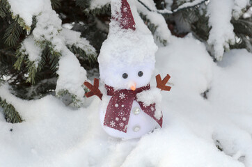 snowman standing under a snowy tree